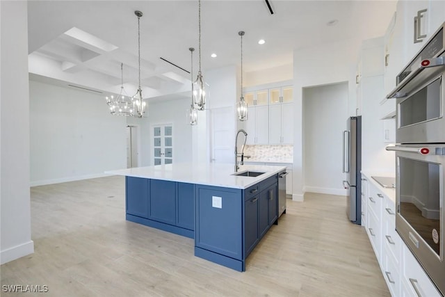 kitchen with blue cabinets, a sink, backsplash, coffered ceiling, and stainless steel appliances