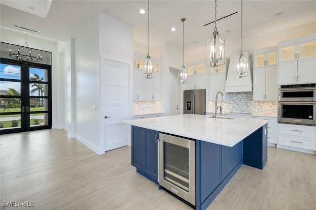 kitchen with wine cooler, light countertops, appliances with stainless steel finishes, blue cabinets, and a sink