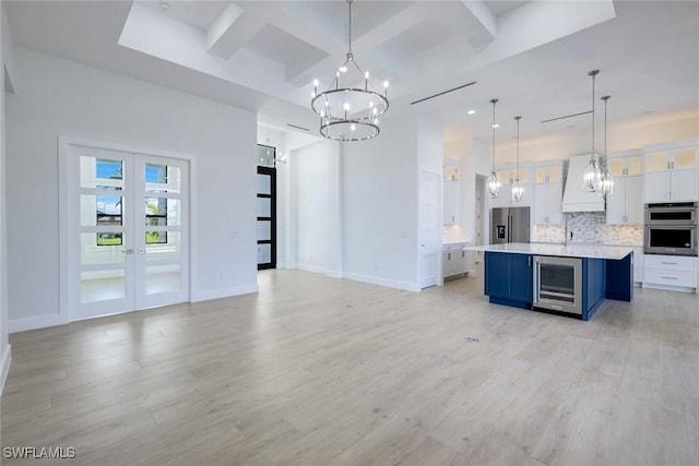 kitchen featuring beverage cooler, decorative backsplash, appliances with stainless steel finishes, white cabinetry, and open floor plan