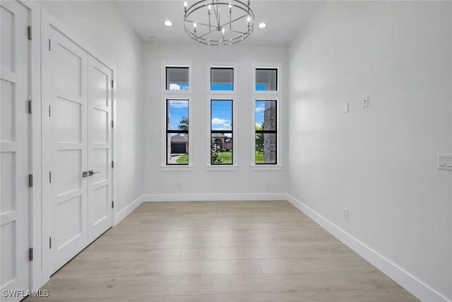 foyer entrance featuring a notable chandelier, baseboards, and light wood-style floors