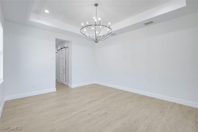 2811 SW 34th Ter, Cape Coral, FL 33914 - empty room featuring a tray ceiling, a barn door, a chandelier, recessed lighting, and light wood-style floors