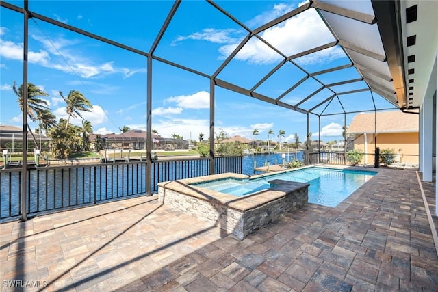 view of pool featuring glass enclosure, a pool with connected hot tub, a patio, and a water view