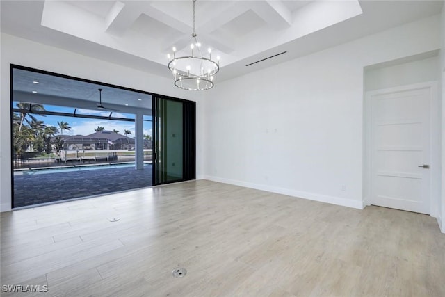 spare room featuring beamed ceiling, coffered ceiling, wood finished floors, baseboards, and a chandelier