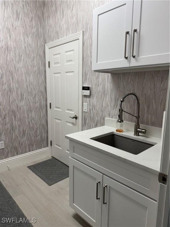 interior space with wallpapered walls, baseboards, and a sink