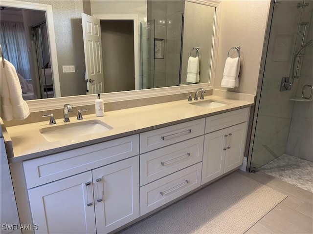 full bathroom featuring double vanity, a stall shower, and a sink