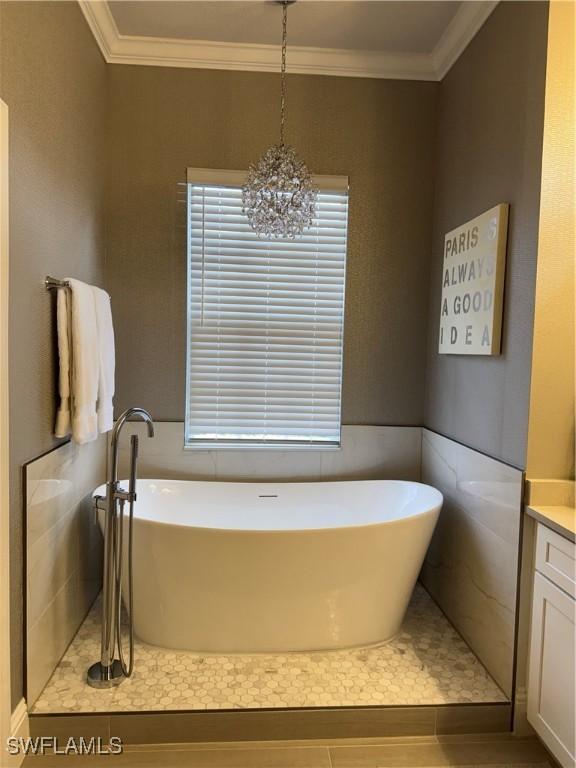 bathroom featuring a freestanding tub, vanity, and crown molding