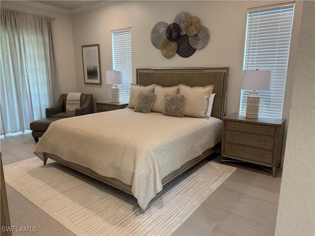 bedroom with multiple windows, ornamental molding, and wood finished floors