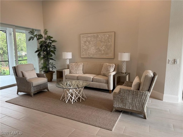 living area with a high ceiling, baseboards, and wood finished floors