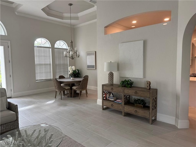 dining room with arched walkways, wood finish floors, crown molding, a chandelier, and baseboards