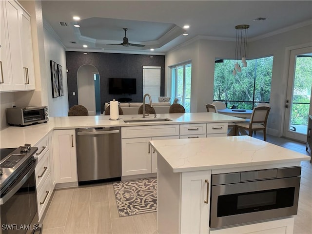 kitchen with a toaster, arched walkways, appliances with stainless steel finishes, a peninsula, and a sink