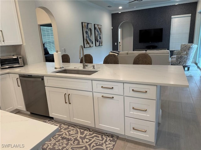 kitchen featuring a toaster, dishwasher, crown molding, white cabinetry, and a sink