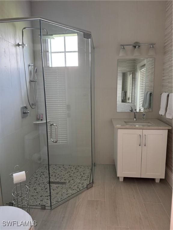 bathroom featuring a shower stall, toilet, and vanity