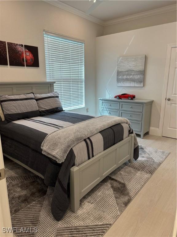 bedroom featuring baseboards, light wood-style floors, and crown molding