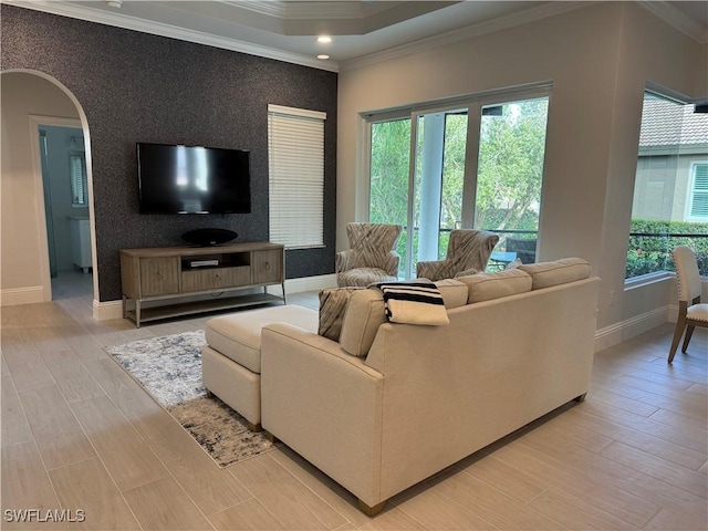 living room featuring an accent wall, arched walkways, ornamental molding, and wallpapered walls