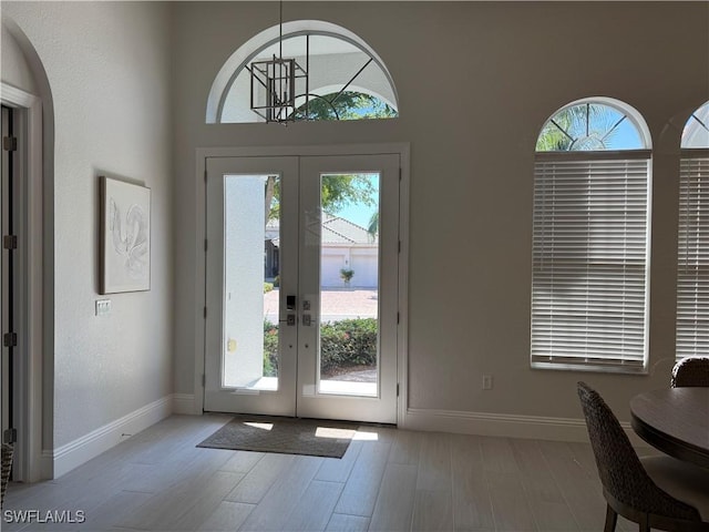 doorway featuring baseboards, wood finished floors, and french doors