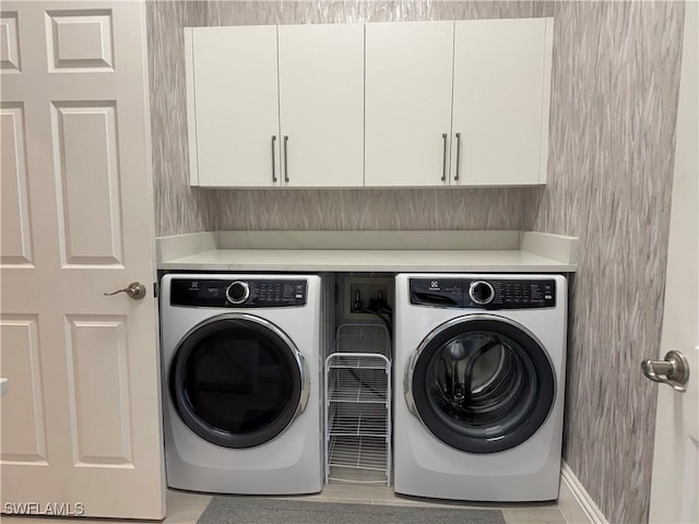 clothes washing area featuring cabinet space and washing machine and clothes dryer