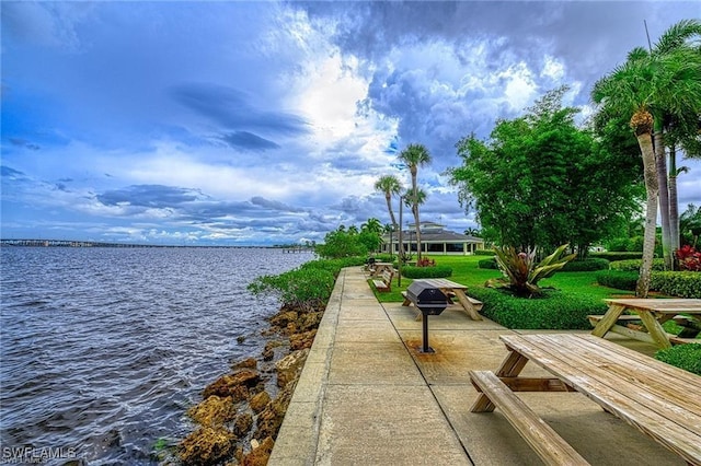 view of dock featuring a patio area, a lawn, and a water view