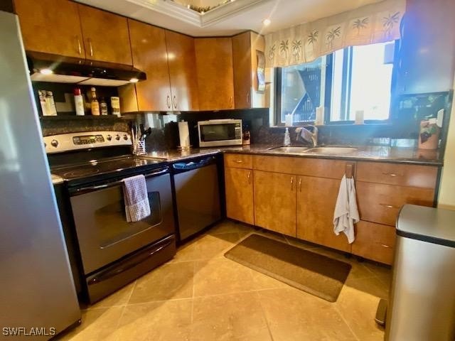 kitchen featuring light tile patterned floors, under cabinet range hood, a sink, appliances with stainless steel finishes, and brown cabinets