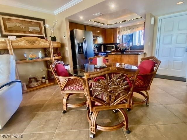 kitchen with light tile patterned floors, brown cabinetry, dark countertops, ornamental molding, and stainless steel appliances