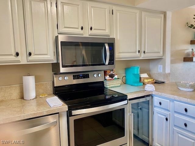 kitchen featuring appliances with stainless steel finishes, white cabinets, and light countertops