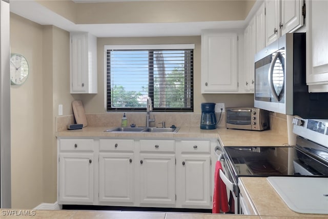 kitchen with appliances with stainless steel finishes, white cabinets, and a sink