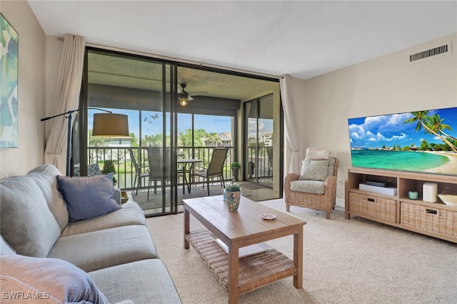 living room with a ceiling fan, visible vents, a wall of windows, and carpet flooring