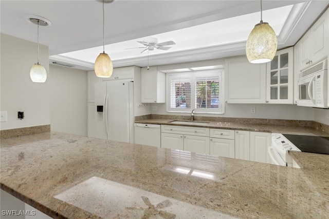 kitchen with stone countertops, white appliances, a sink, a tray ceiling, and glass insert cabinets