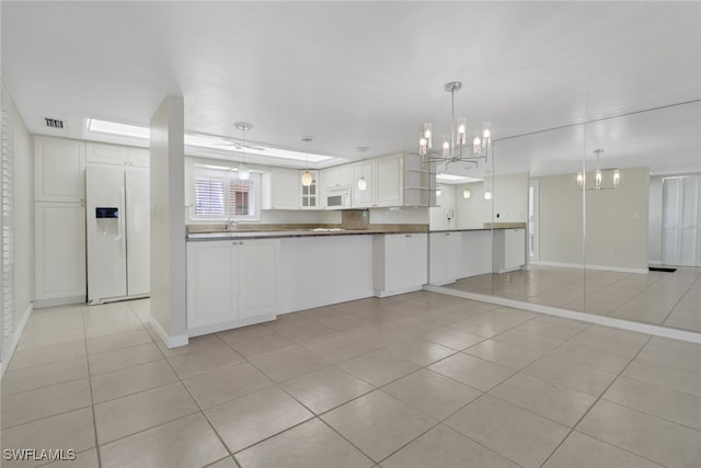 kitchen featuring a notable chandelier, light tile patterned floors, dark countertops, white cabinetry, and white appliances