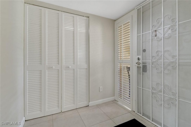 doorway with baseboards and tile patterned floors