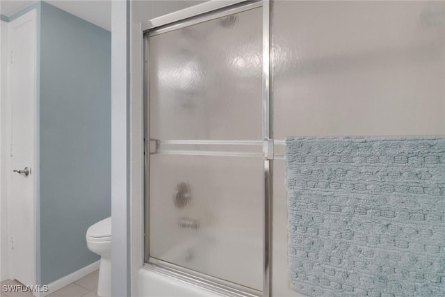 bathroom featuring toilet, tile patterned flooring, and enclosed tub / shower combo