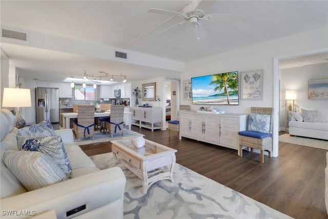 living area with dark wood-type flooring, visible vents, and ceiling fan