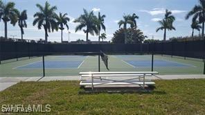 view of tennis court with a yard and fence