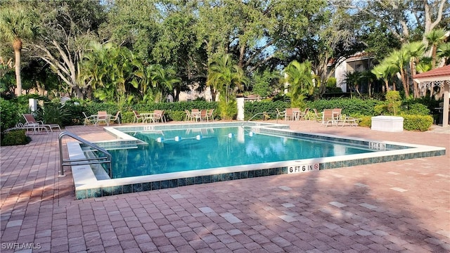 community pool with a patio and fence