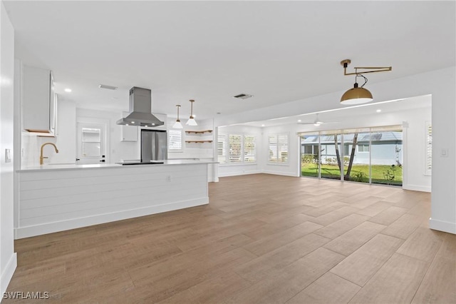 unfurnished living room with recessed lighting, a sink, visible vents, baseboards, and light wood finished floors