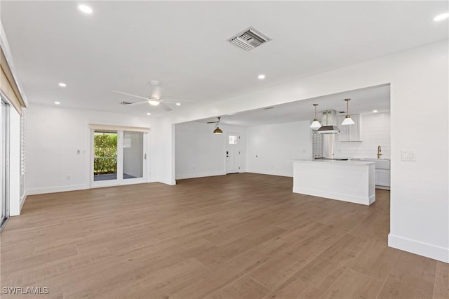 unfurnished living room featuring ceiling fan, recessed lighting, wood finished floors, visible vents, and baseboards