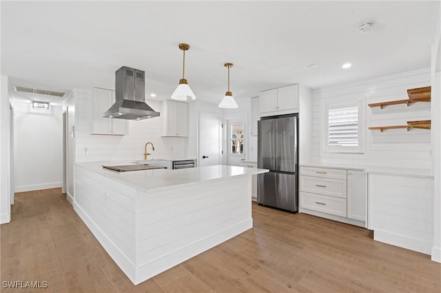 kitchen featuring island exhaust hood, open shelves, freestanding refrigerator, a peninsula, and black electric cooktop