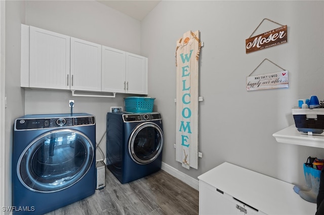 laundry area featuring wood finished floors, washing machine and dryer, cabinet space, and baseboards