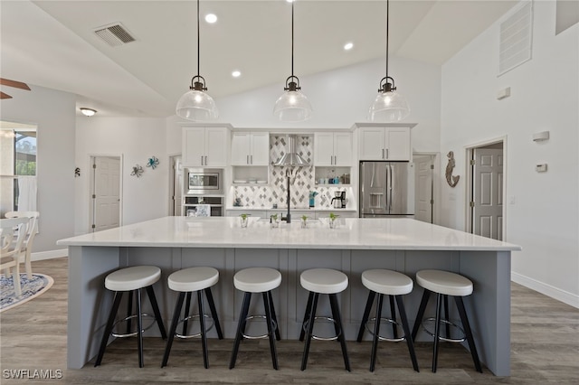 kitchen featuring a breakfast bar, a large island, stainless steel appliances, visible vents, and white cabinets