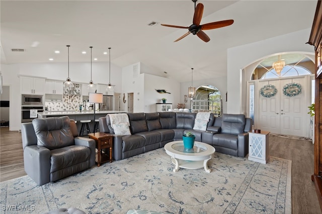 living room featuring recessed lighting, visible vents, light wood-style flooring, high vaulted ceiling, and ceiling fan with notable chandelier