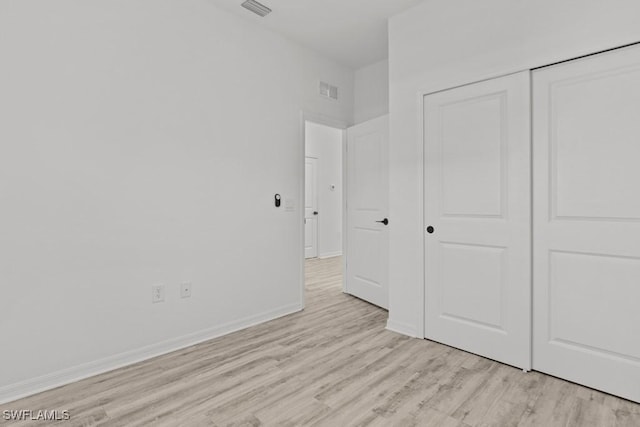 unfurnished bedroom featuring light wood finished floors, visible vents, baseboards, and a closet