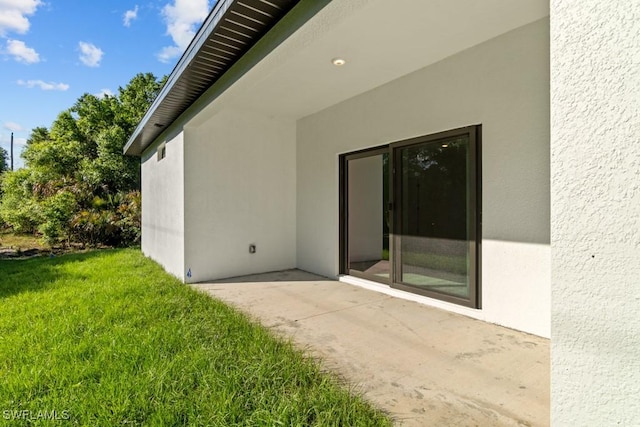 doorway to property with a yard and stucco siding