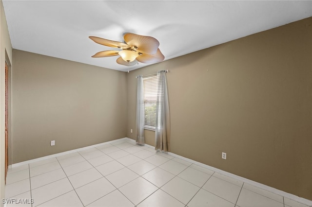 empty room with light tile patterned floors, baseboards, and a ceiling fan