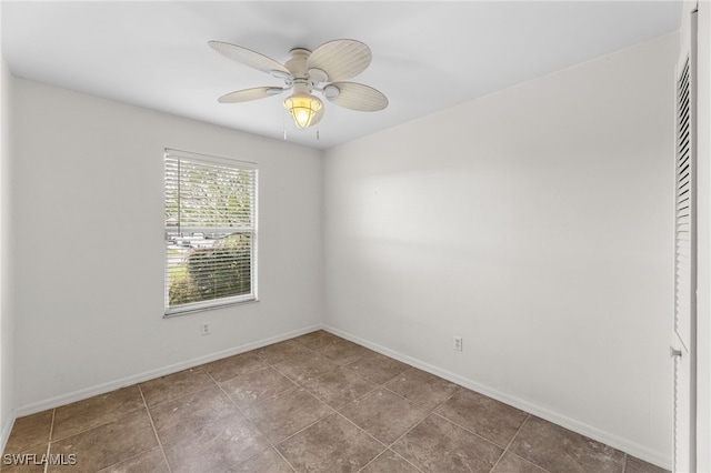 tiled empty room with a ceiling fan and baseboards