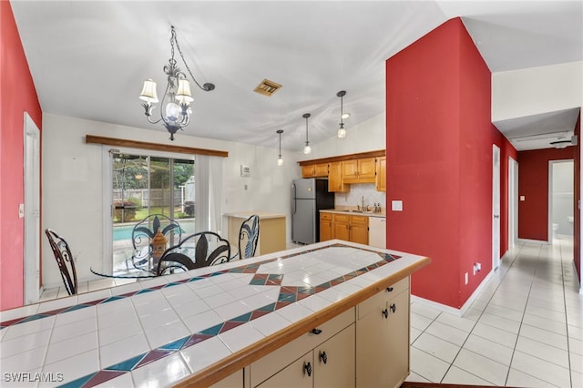 kitchen featuring light tile patterned floors, visible vents, freestanding refrigerator, vaulted ceiling, and white dishwasher