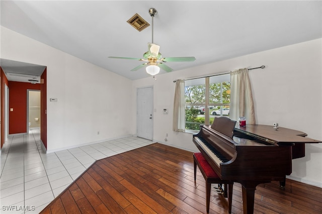 sitting room with light wood finished floors, visible vents, vaulted ceiling, and a ceiling fan