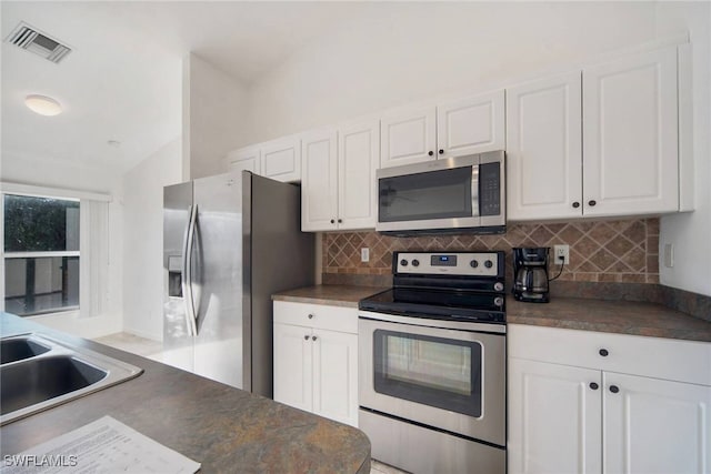 kitchen with stainless steel appliances, dark countertops, visible vents, decorative backsplash, and white cabinetry