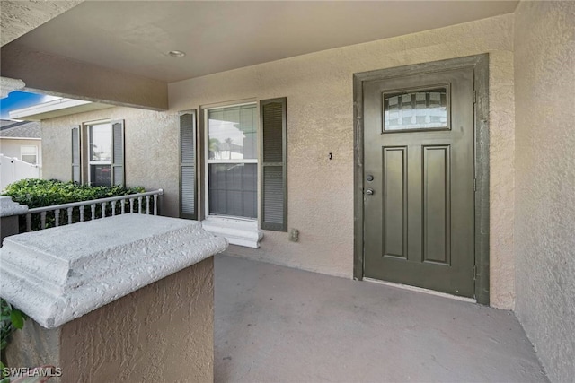 doorway to property featuring a porch and stucco siding