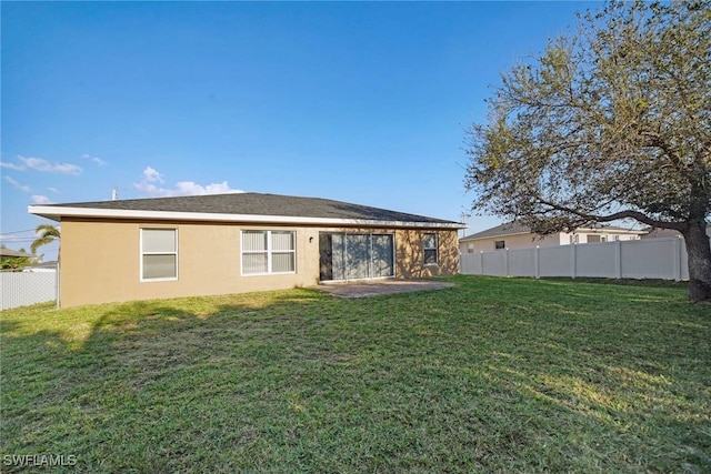 rear view of property with a yard, fence, and stucco siding