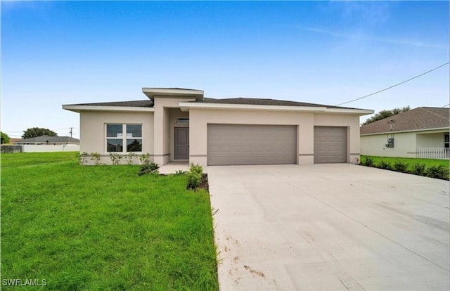 prairie-style home featuring a front yard, concrete driveway, and stucco siding