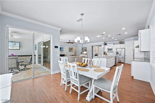 dining space with ornamental molding, visible vents, and ceiling fan with notable chandelier